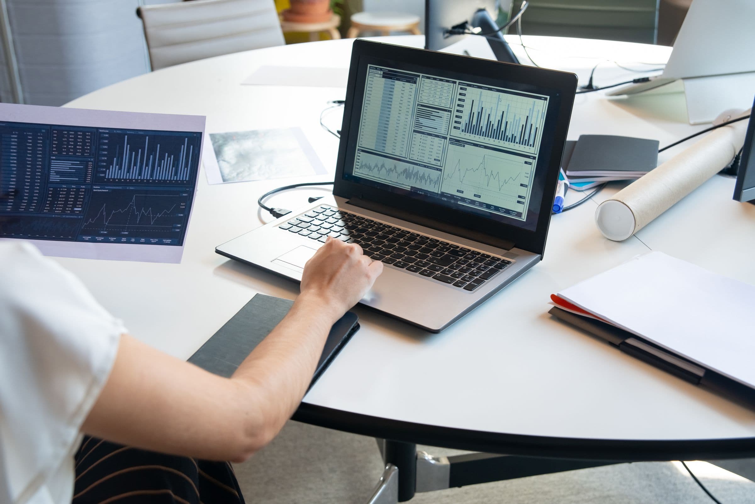 A compensation analyst reviewing pay data and charts on a laptop