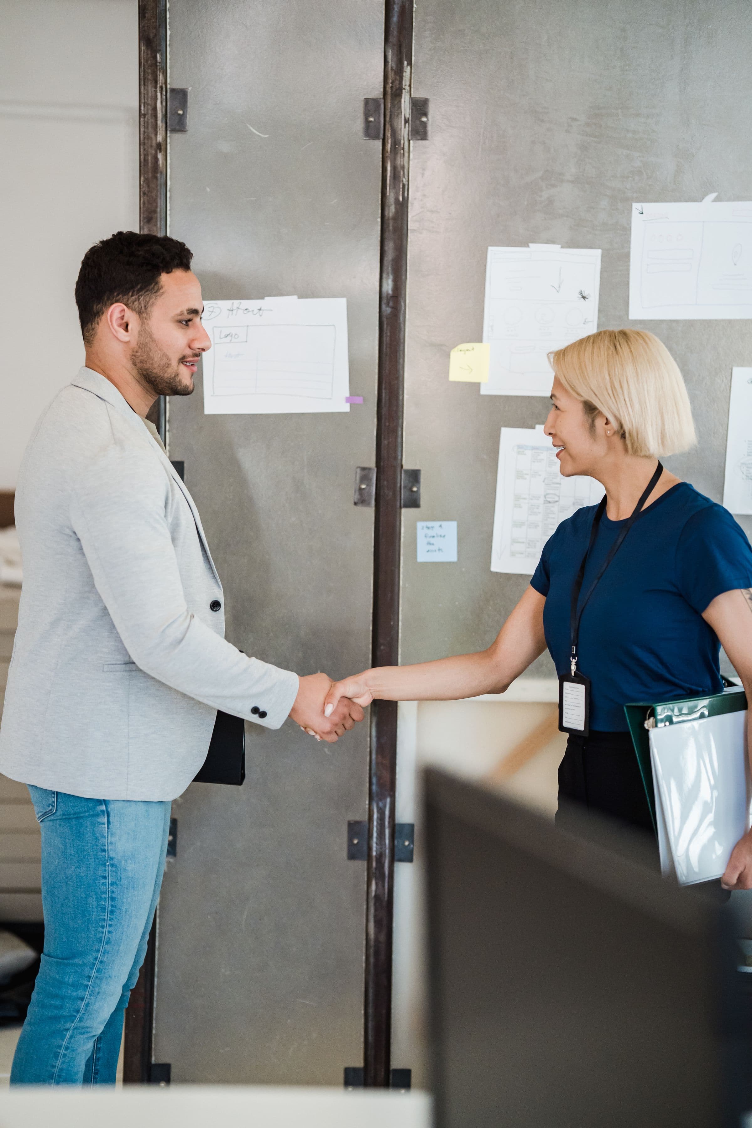 Two colleagues shaking hands in a modern office, welcoming a new team member