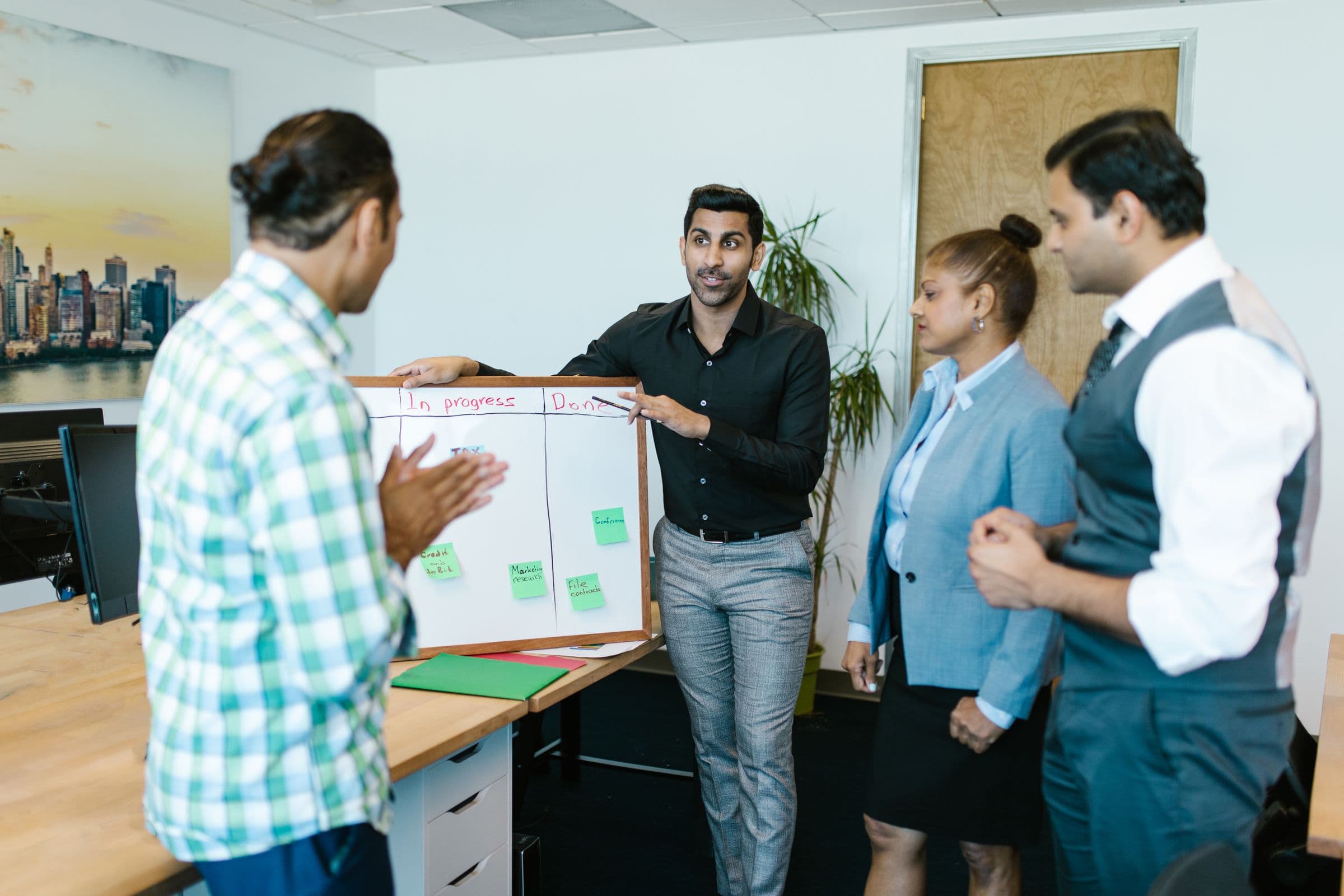 A team gathered around a whiteboard tracking project tasks in progress and done